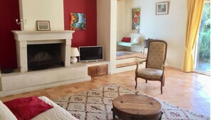 Ein Wohnzimmer mit Kamin, Fernseher, einem Sessel und einem gemusterten Teppich.