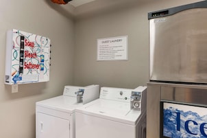Zona de lavandería con un letrero que indica uso para huéspedes, un refrigerador Prodigy y una lavadora Whirlpool.