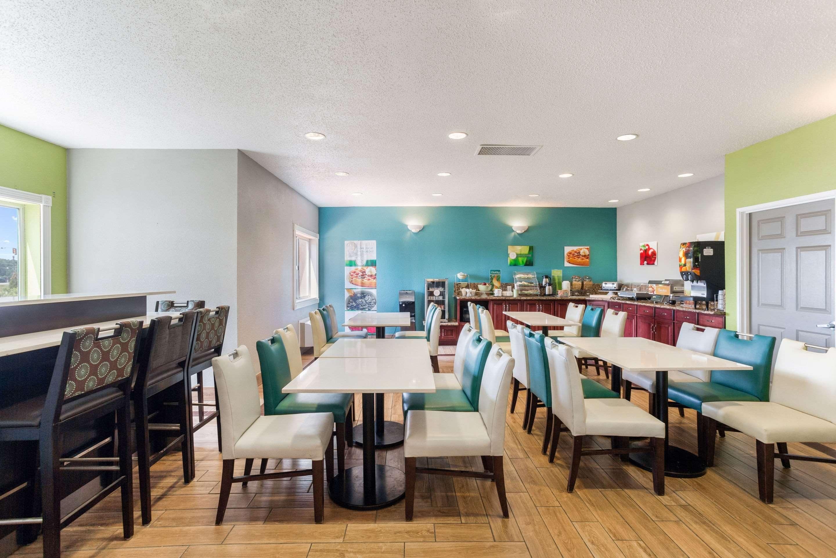 Un restaurante con varias mesas, cabinas, una barra y una zona de cocina al fondo.