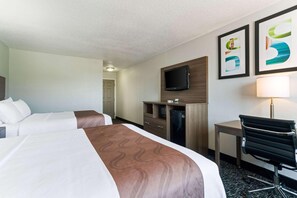 A hotel room with two beds, a desk, a chair, a TV, and artwork on the wall. - Quality Inn & Suites Ferdinand (Ferdinand)