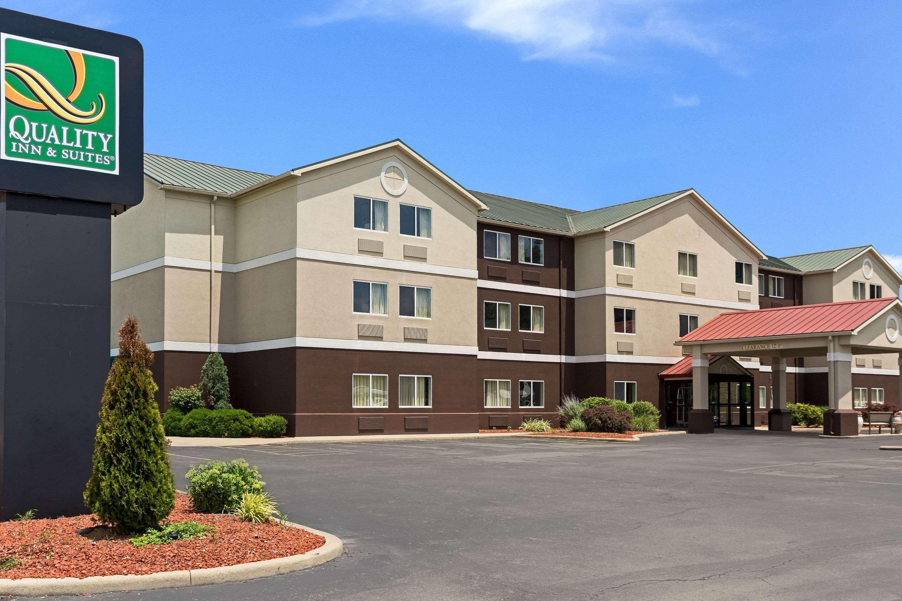 A multi-story hotel with a sign for Quality Inn & Suites, a covered entrance, and a parking lot.