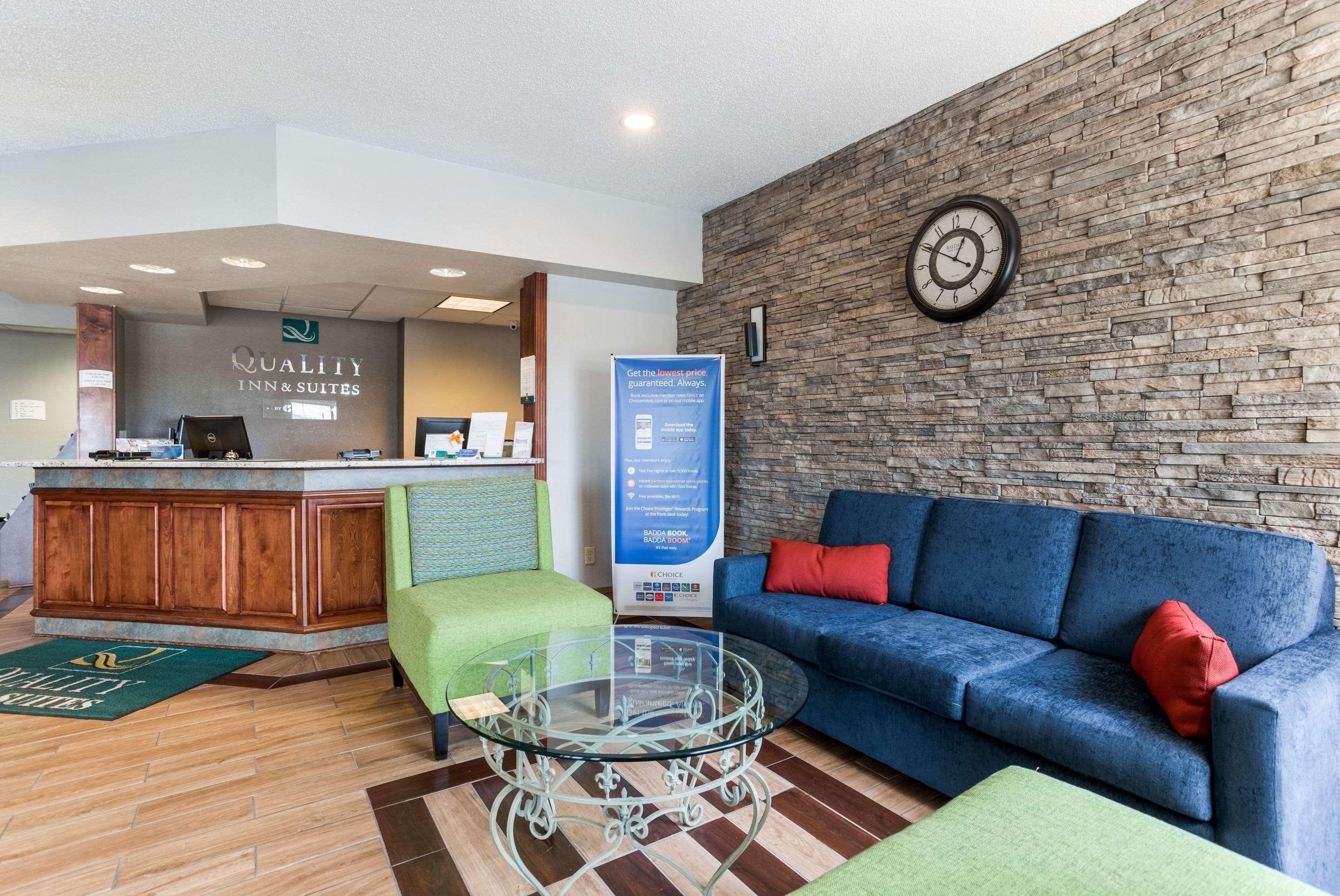 A reception area with a reception desk, a clock, a blue sofa, and a glass coffee table.