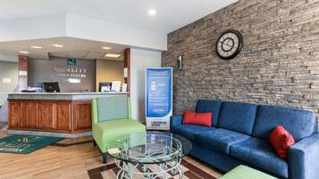 A reception area with a reception desk, a clock, a blue sofa, and a glass coffee table.