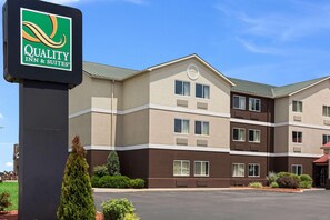 A multi-story hotel with a sign for Quality Inn & Suites, featuring a modern design with a flat roof and a parking lot in front. - Quality Inn & Suites Ferdinand (Ferdinand)