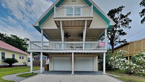 A two-story house with a balcony, a garage, and a well-maintained lawn. - Sandys Beach House | Pet Friendly, Close to Beach! (Tybee Island)
