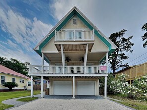 Una casa a due piani con un balcone, un garage e un prato curato.