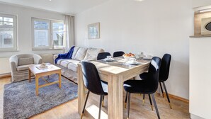Ein modernes Wohnzimmer mit Essbereich, ausgestattet mit einer Couch, einem Couchtisch und einem Esstisch mit Stühlen.