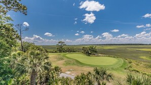Un parcours de golf avec un ciel dégagé, une végétation luxuriante et quelques nuages épars.