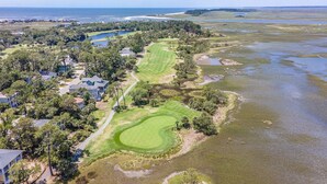 Un parcours de golf avec un plan d’eau, entouré de maisons résidentielles et de verdure.