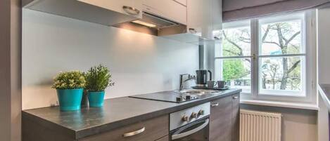 Een koelkast, een oven, een waterkoker, kookgerei, borden en bestek