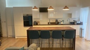 Une cuisine moderne avec un îlot central, des tabourets de bar et des luminaires suspendus.