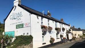 Un bâtiment blanc avec une enseigne indiquant « The Globe Inn » et une banderole annonçant : « Notre jardin à bière est maintenant ouvert ».