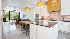 A modern kitchen with white cabinets, a central island, and pendant lighting.