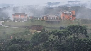 A residential area with houses on a hillside, surrounded by greenery and fog. - Pousada Caminhos da Vila Chantal (Campos do Jordão)