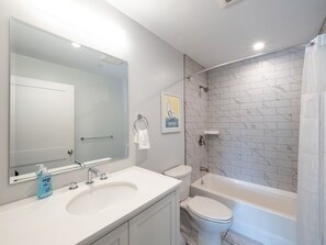 Ein modernes Badezimmer mit Waschbecken, Toilette und Badewanne in Weiß.