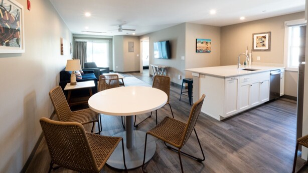 A modern apartment with a dining area, kitchen, living room, and a large window.