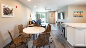 A modern kitchen with a round dining table, wicker chairs, and a white countertop.