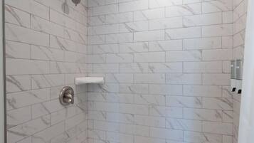 A modern bathroom with a freestanding bathtub, a showerhead, and a towel rack.