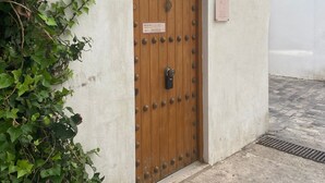 A wooden door with a brass knocker, a number 7 above it, and a small sign with a building's name. - Casa Africa (Tarifa)