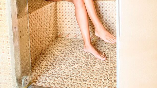 A person sitting in a shower with a patterned tile wall and floor. - Casa Africa (Tarifa)