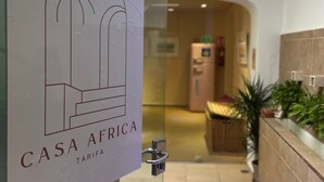 A modern hotel lobby with a glass partition displaying the logo 'CASA AFRICA TARIFA'. - Casa Africa (Tarifa)
