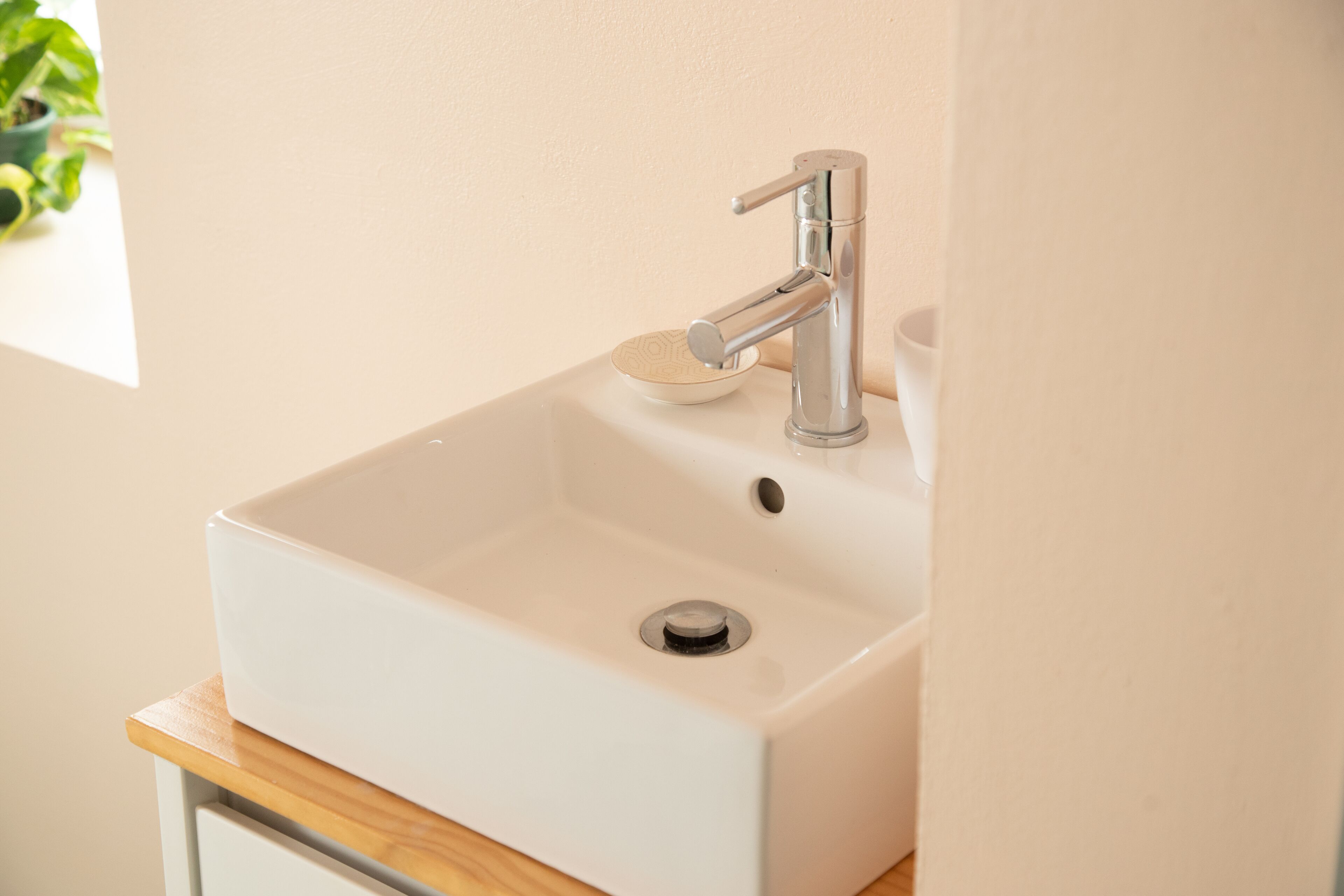 A white bathroom sink with a modern faucet and a small bowl on the countertop.