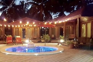 A pool area with a hot tub, wooden deck, and outdoor seating. - Marbucks Bed and Breakfast (San Pedro)