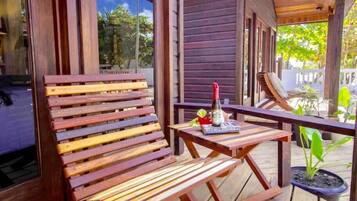 Eine Holzterrasse mit einer Bank, einem kleinen Tisch, einem Blumentopf und einer Wasserflasche.