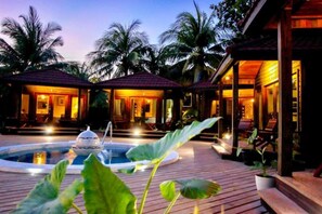 Un resort con piscina, terraza de madera y palmeras.