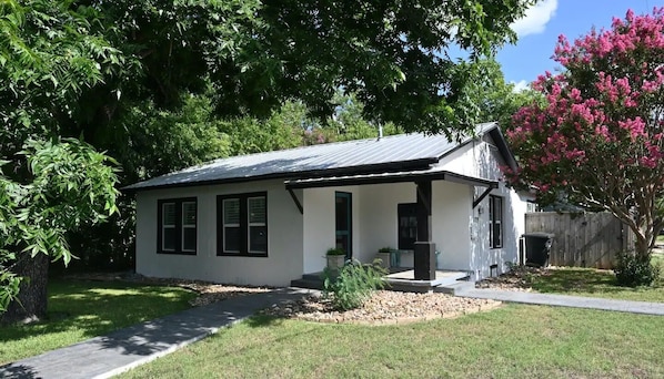 A single-story house with a covered porch, a front door, and a small front yard with a pathway leading to the entrance.