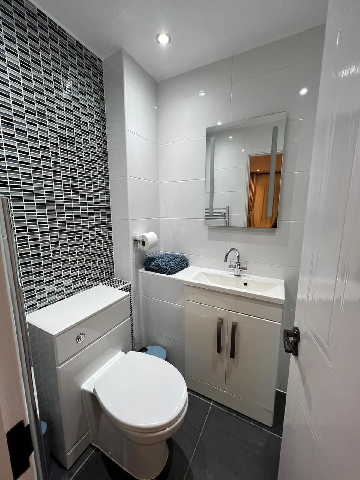 A modern bathroom with a toilet, sink, and mirror.