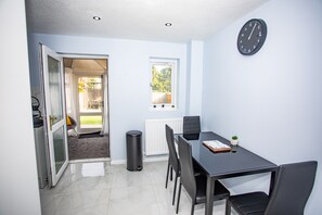 Una habitación moderna con una mesa de comedor, sillas, un reloj y vistas al exterior.