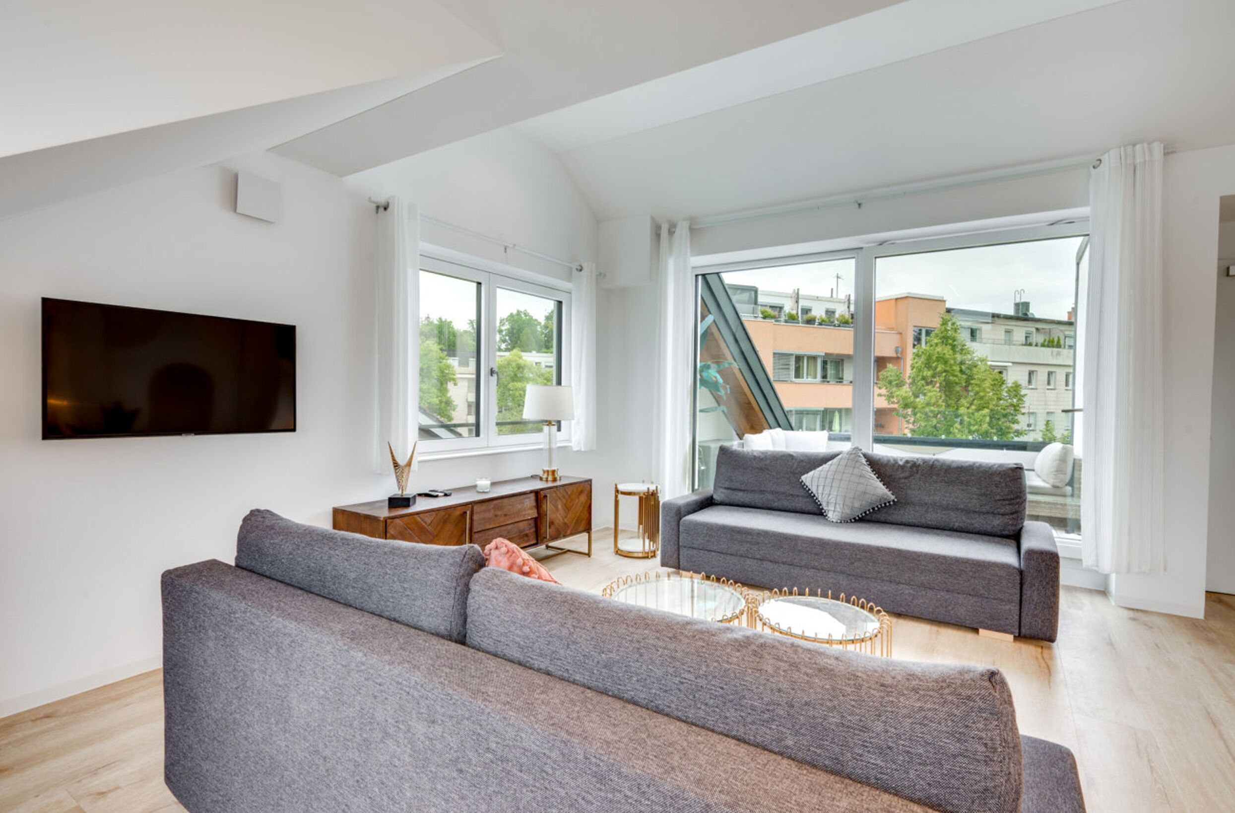 A modern living room with a grey sofa, a coffee table, and a TV mounted on the wall.