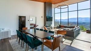A modern interior with a dining area, a large sofa, and a view of the mountains. - 3 Pines Lodges: Luxury, Mountain View, & Hot Tub! (Sevierville)