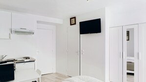 Een slaapkamer met een bed, een bureau met een computer, een televisie en een kledingkast.