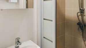 Een badkamer met een douche, een wastafel en een spiegel.