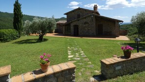 A stone building with a tiled roof, a chimney, and a paved pathway leading to the entrance. - SCAPPO IN UMBRIA, La Vallata (Cantone)