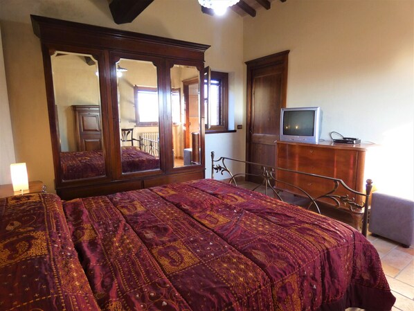 Un dormitorio con una cama grande, un aparador, un televisor y un espejo.