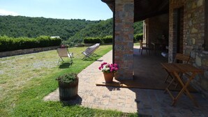 A covered patio with a stone wall, a wooden table, and two chairs. - SCAPPO IN UMBRIA, La Vallata (Cantone)