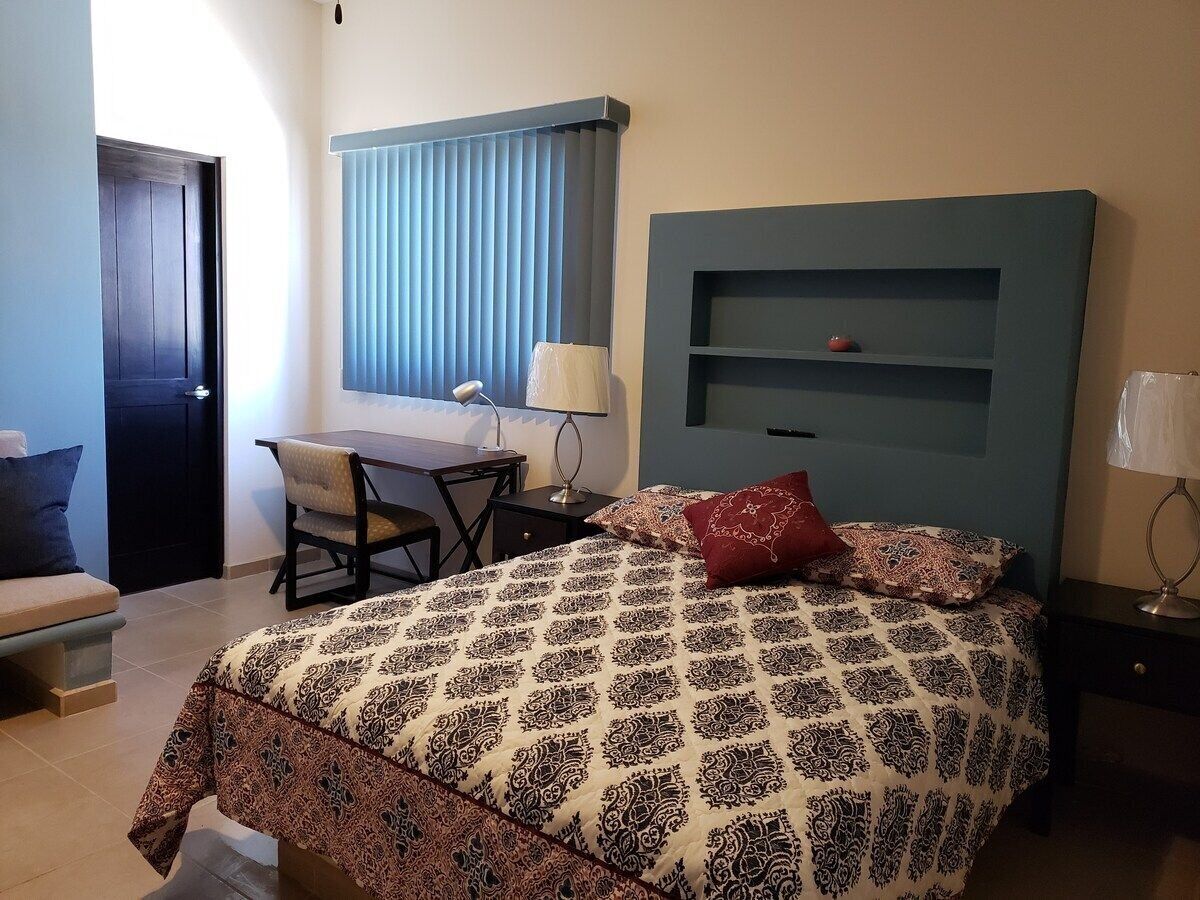 A bedroom with a bed, a desk, and a chair.
