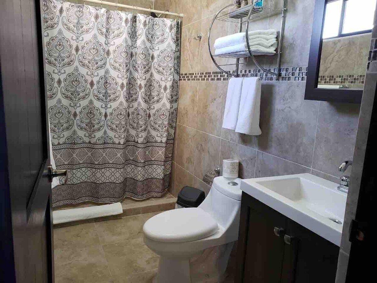 A bathroom with a patterned shower curtain, a toilet, a sink, and a towel rack.