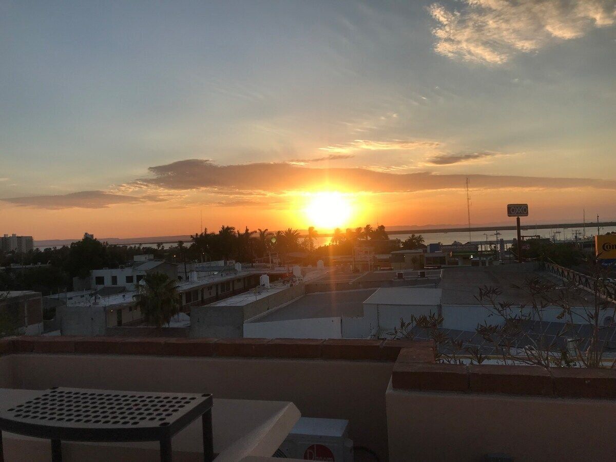 A sunset view from a rooftop terrace with buildings in the background.