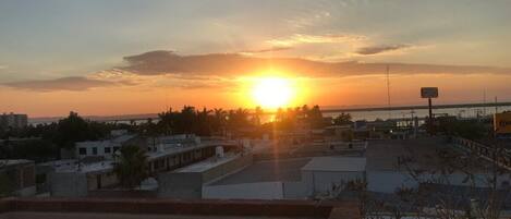 A sunset view from a rooftop terrace with buildings in the background.