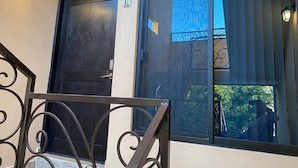 Entrada de um edifício com porta de madeira escura e uma janela grande com grade de metal.