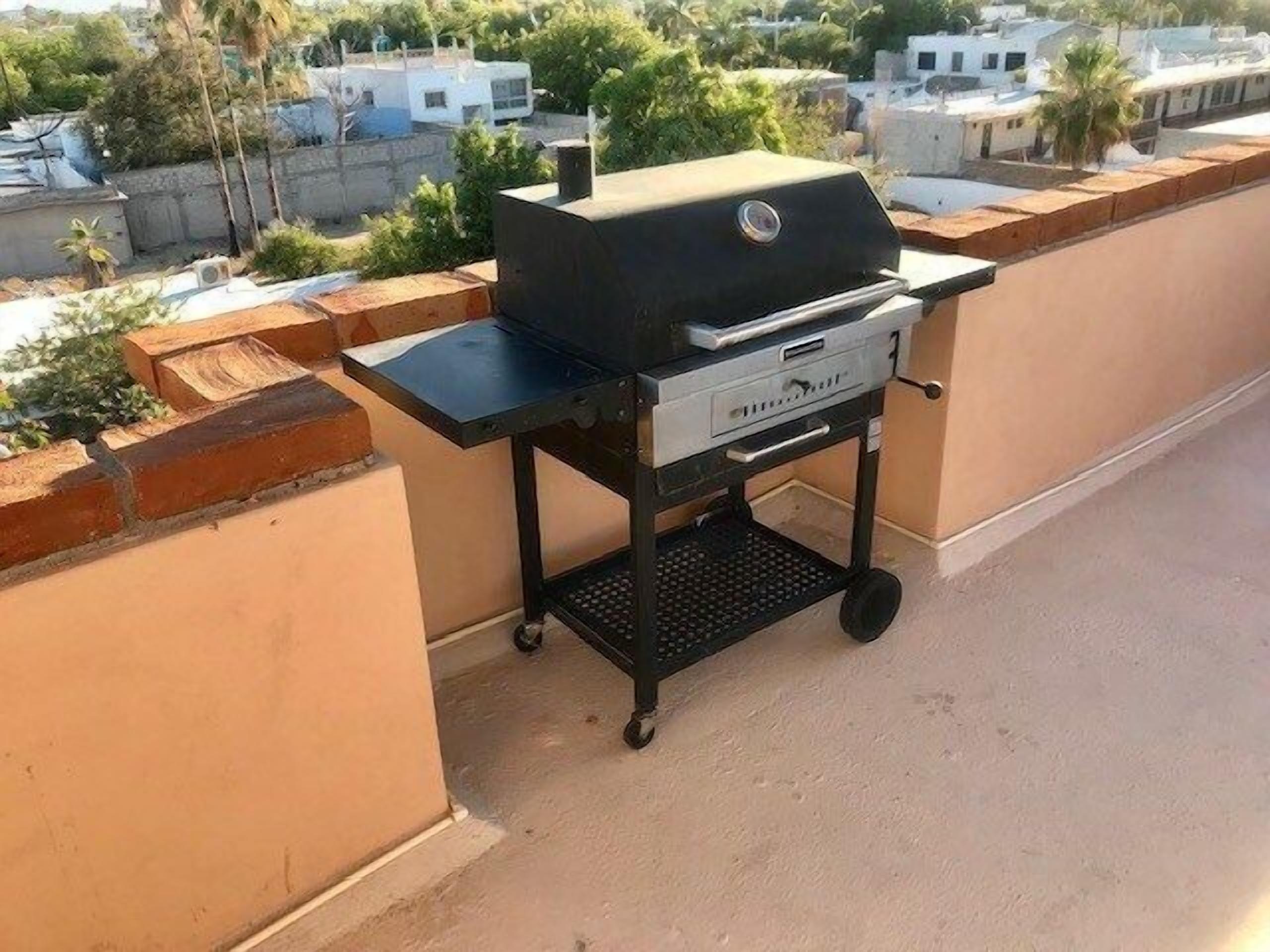 A portable grill on a balcony with a city view.