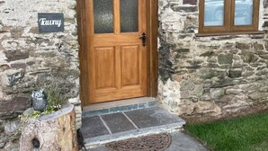 A stone building with a wooden door and a small window. - Tawny Cottage pet friendly, barn conversion, quiet farm location, nr Dartmouth. (Dartmouth)