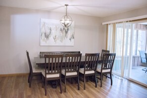 A dining area with a wooden table and chairs, a chandelier, and a large abstract painting on the wall. - The Bavarian Resort (Branson)