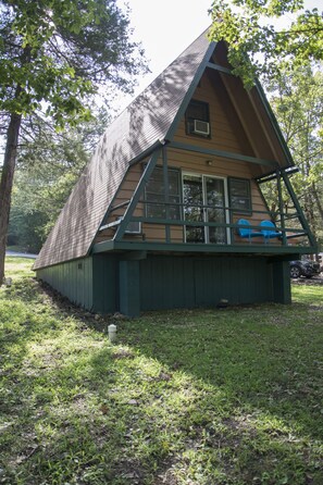 A wooden cabin with a pitched roof, a porch with blue chairs, and a small window. - The Bavarian Resort (Branson)