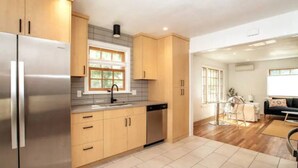 Une cuisine moderne avec des meubles en bois, un réfrigérateur en acier inoxydable et une fenêtre au-dessus de l’évier.