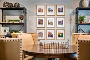 A dining area with a round table, chairs, and framed cityscape photographs on the wall.